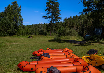 Inflatable rubber boats for rafting on the river lie near the shore.