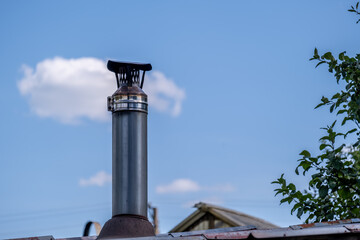 An iron chimney on the roof of a house in close-up.