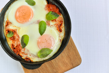 scrambled eggs baked in a frying pan on a wooden background