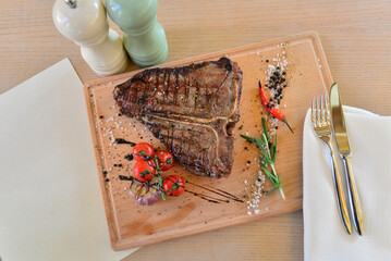 large steak of grilled meat on a wooden board on a table with wine