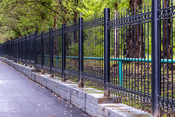 A long iron fence on a concrete base.