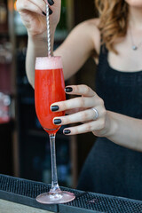 A girl is making a cocktail in a glass at the bar counter
