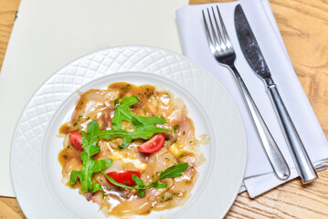 Scallop carpaccio in a white plate on the table