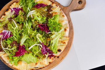 Vegetarian pizza with salad on a wooden board