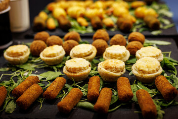 Mini savory snacks and pastries arranged on arugula leaves