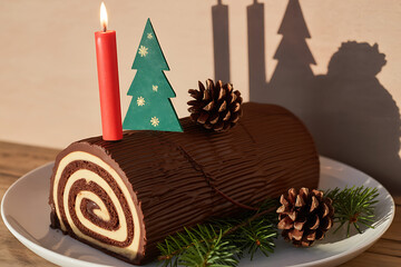 Festive chocolate cake with pinecones, miniature trees, and a lit candle evokes holiday cheer.
