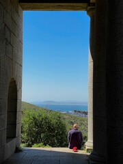 A tourist sits in a beam of sunlight admiring the view from Rhodes Memorial in Cape Town, South Africa.