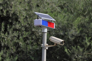 CCTV camera with solar panel on a pole in the park.