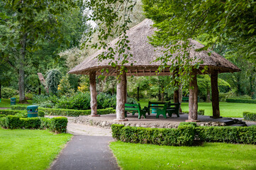 Wooden gazebo with thatched roof, located in the green area of the park. Ideal spot for outdoor relaxation and gatherings.