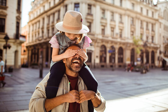 Young girl playing with father in city