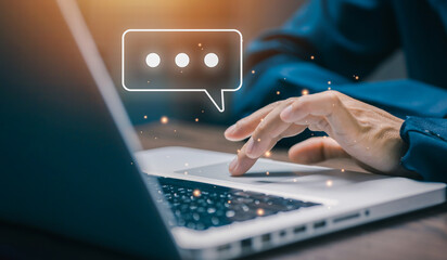 Business hand typing on laptop with floating chat bubble icon. Concept of digital communication,...