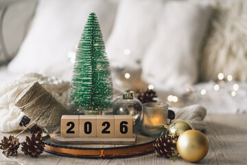 Decorative candles and a small Christmas tree create a cozy scene celebrating the New Year in winter 2026