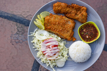 Two crispy fried fish fillets served with rice, salad, and spicy Thai dipping sauce.
