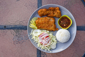 Two crispy fried fish fillets served with rice, salad, and spicy Thai dipping sauce.