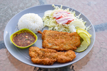 Two crispy fried fish fillets served with rice, salad, and spicy Thai dipping sauce.