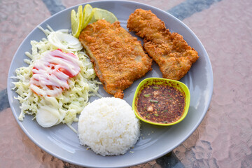 Two crispy fried fish fillets served with rice, salad, and spicy Thai dipping sauce.