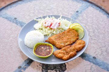 Two crispy fried fish fillets served with rice, salad, and spicy Thai dipping sauce.
