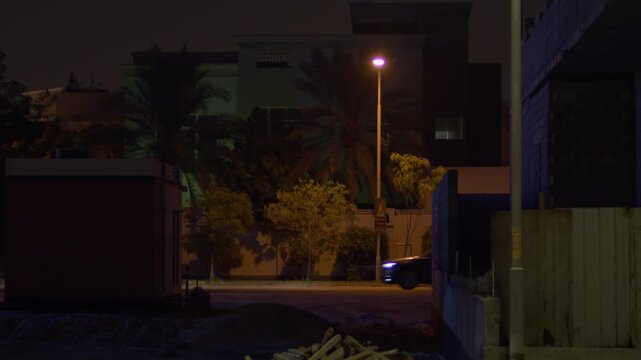 Cars and single pedestrian passing, street in Sar, Bahrain, at night