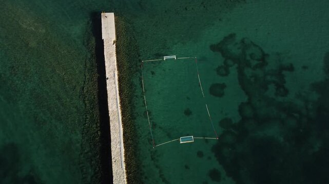 water polo field by the sea, by the concrete jetty, sunny day, summer, calm sea, view from a drone