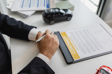 A businessman in a suit is calculating loan details, reviewing financial documents, and holding car...