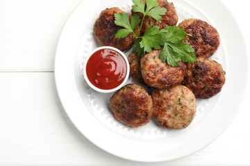 Delicious patties with parsley and ketchup on white wooden table, top view. Space for text