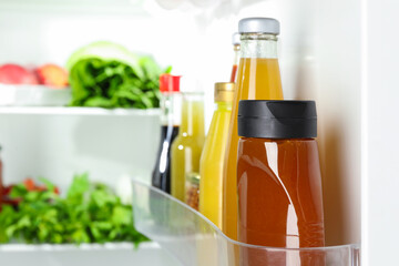 Bottles with different tasty sauces and products in fridge, closeup