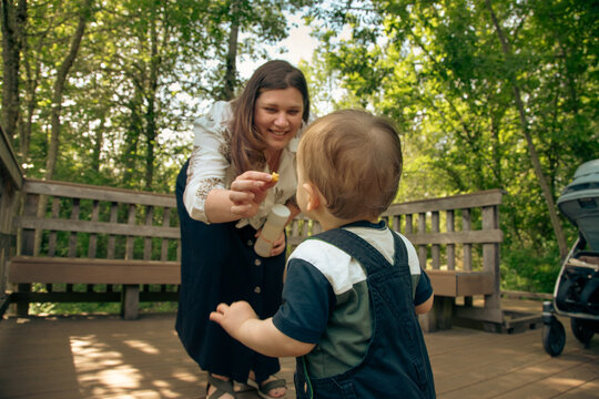 Smiling woman standing on a wooden deck giving her son a treat