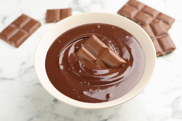 Melted chocolate and pieces on white marble table, closeup