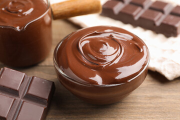 Melted chocolate and pieces on wooden table, closeup
