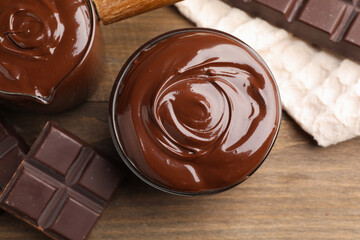 Melted chocolate and pieces on wooden table, flat lay