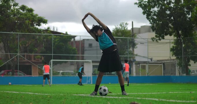 Hispanic man stretching and warming up on soccer field before game, performing athletic movements to prepare body and mind for match with focus and coordination in outdoor park