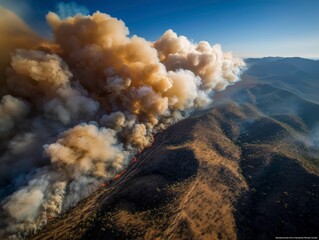 Wide aerial view of a massive forest fire releasing smoke over dry hills and valleys during heatwave
