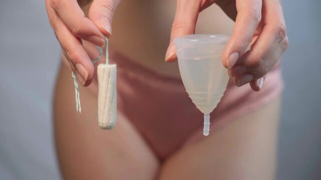 Close-up of female body with menstrual cup in hand. Feminine hygiene choice, woman health care routine and self-awareness. Daily care and the female cycle. Women health, menstruation or period