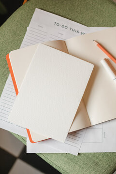 Close-up overhead view of a to do list on a chair with an open notebook, pen and pencil