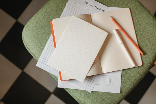 Close-up overhead view of a to do list on a chair with an open notebook, pen and pencil