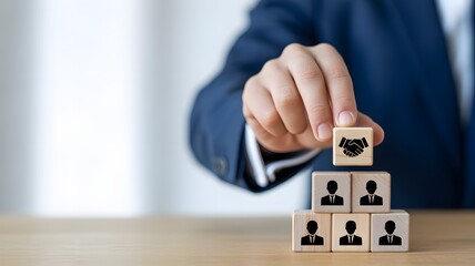Hand placing person icon cube on pyramid of business blocks