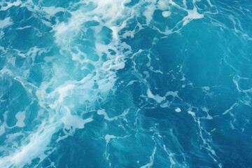 Obraz premium A vibrant, textured surface of blue water with white frothy waves creating a dynamic and refreshing ocean scene.