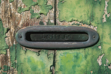 Una buca delle lettere su una porta di legno dalla vernice verde scrostata di una casa di Venezia