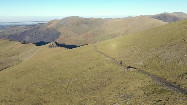 Aerial view of people hiking and climbing Snowdon mount in Wales on a sunny day