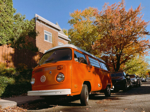 Vieille camionnette orange Volkswagen Westfalia gar&eacute;e dans une rue r&eacute;sidentielle en automne.