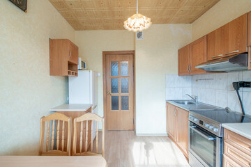 Cozy Wooden Kitchen Home Interior. Oven, Faucet, Kettle, Fridge and Furniture in Background.