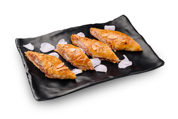 Delicious baked pastries with almonds served on a black plate