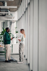 Diverse colleagues discussing work, collaborating in modern office
