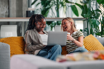 Diverse women friends laughing watching laptop screen