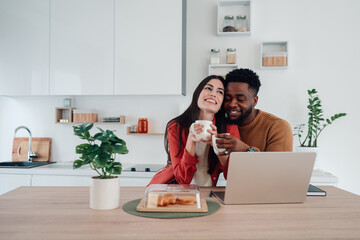 Interracial couple enjoying coffee morning in kitchen