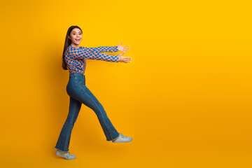A stylish young woman in jeans and a bright patterned top leaps toward viewers with open arms...