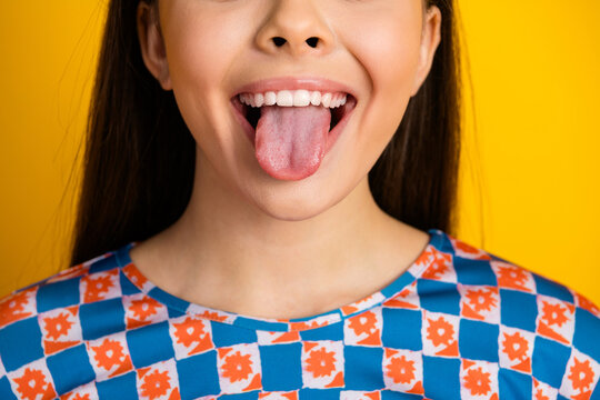 Fototapeta Young girl with tongue out against bright yellow background wearing a blue white orange checkered shirt playful fashion mood