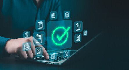 Businessman using laptop to approve digital documents with glowing check mark icon, symbolizing online verification, secure data management, workflow automation, and paperless business process.