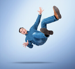 Surprised man in casual clothes falling down with arms spread, on blue gradient background, concept of failure, accident, shock, losing balance, or business risk