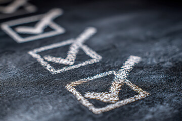 Chalk-drawn check marks inside squares on a blackboard symbolizing completed tasks or goals in a to-do checklist concept with a shallow depth of field effect